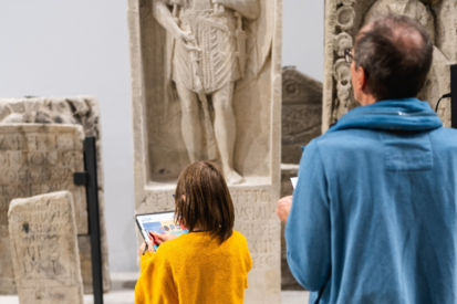Kind und Erwachsener, die sich Steinfiguren im Museum angucken